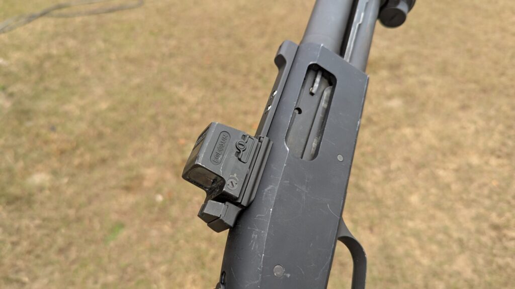 Close-up of a Holosun red dot sight mounted on a shotgun receiver.