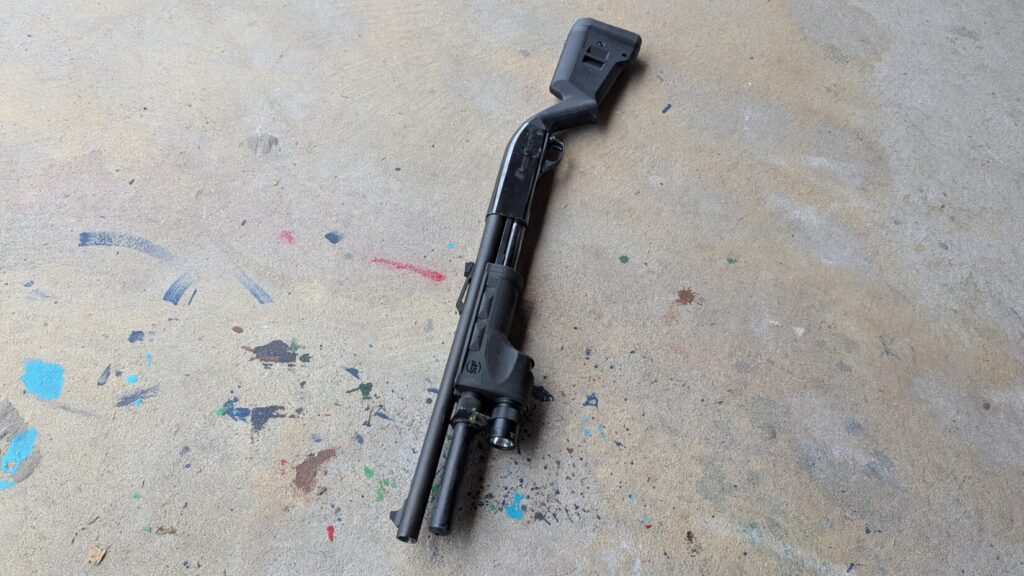 Close-up of a shotgun muzzle resting on concrete.