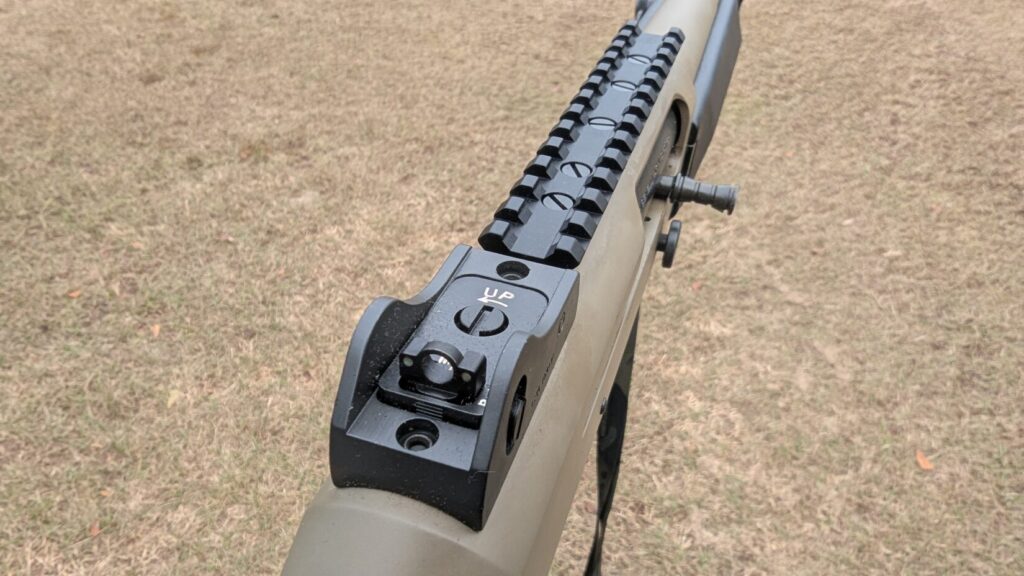 Close-up of the receiver, forend, and barrel of a tan and black semi-automatic shotgun with a sling.