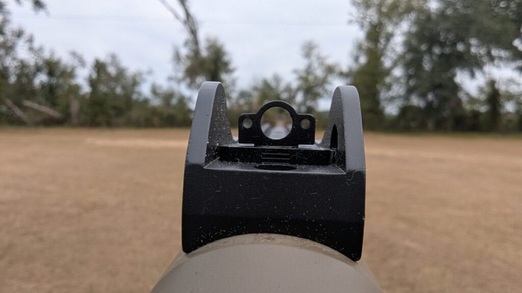Close-up, shooter's-view of a ghost ring rear sight on a shotgun, focused on the sight aperture.