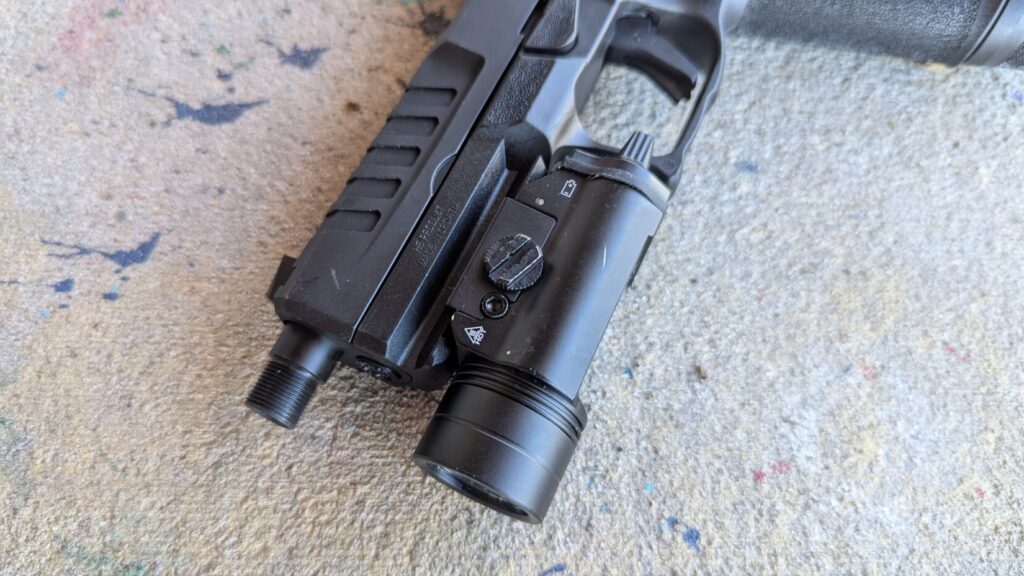 Close-up of a pistol grip, trigger, and a large weapon light mounted on the rail.