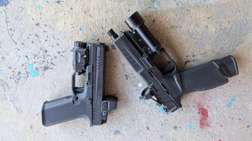 Two semi-automatic pistols with mounted optics and lights on concrete.