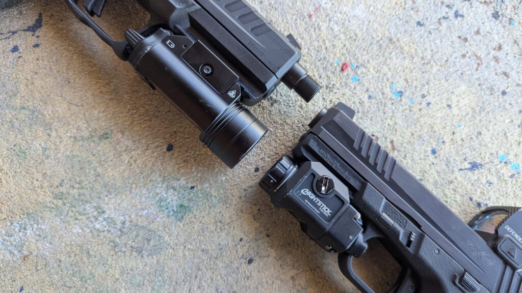 Close-up of two pistols' muzzles and their attached weapon lights.