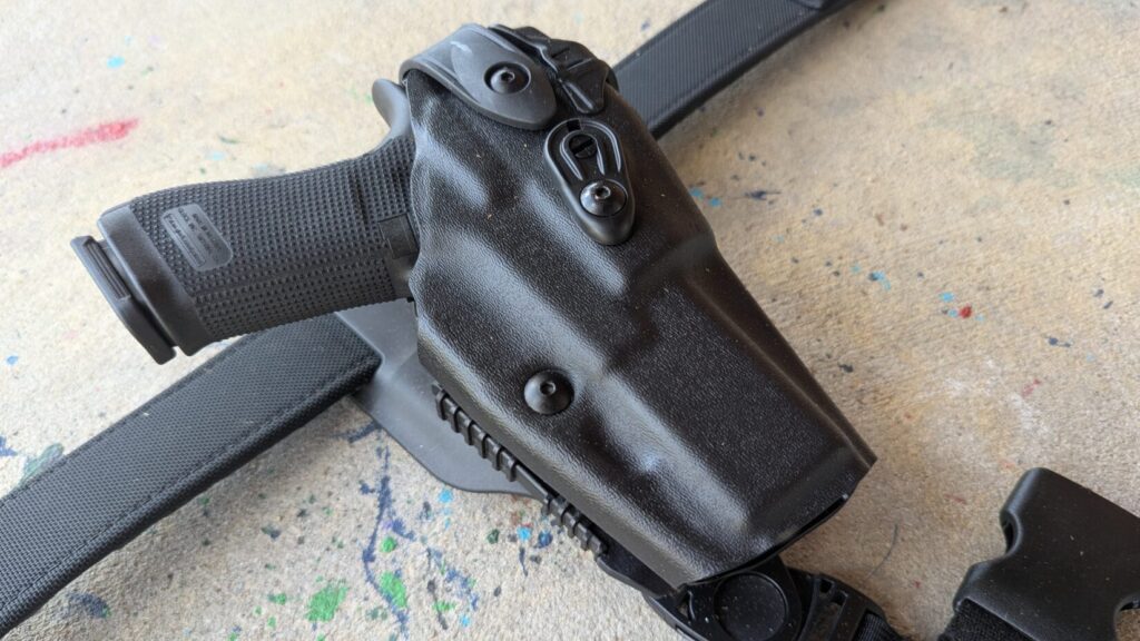 Angled close-up of the 6360RDS holster on a belt, focusing on the SLS rotating hood and the textured grip of the holstered pistol.