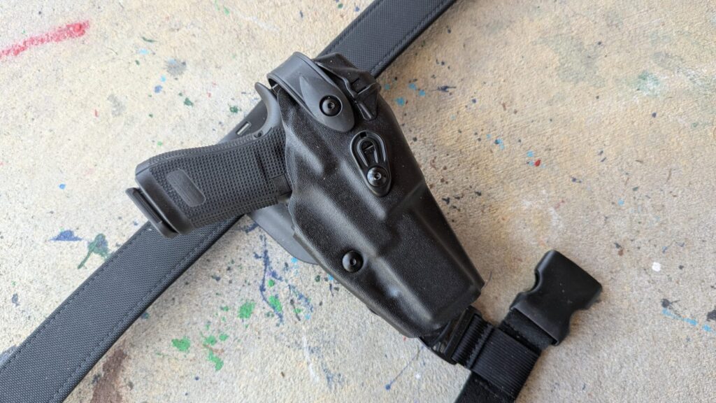 Angled close-up of the 6360RDS holster on a belt, focusing on the SLS rotating hood and the textured grip of the holstered pistol.