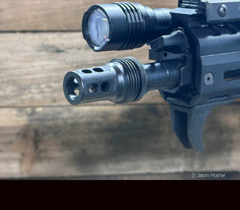 The end of a rifle barrel with an ASR muzzle device connected to it. 