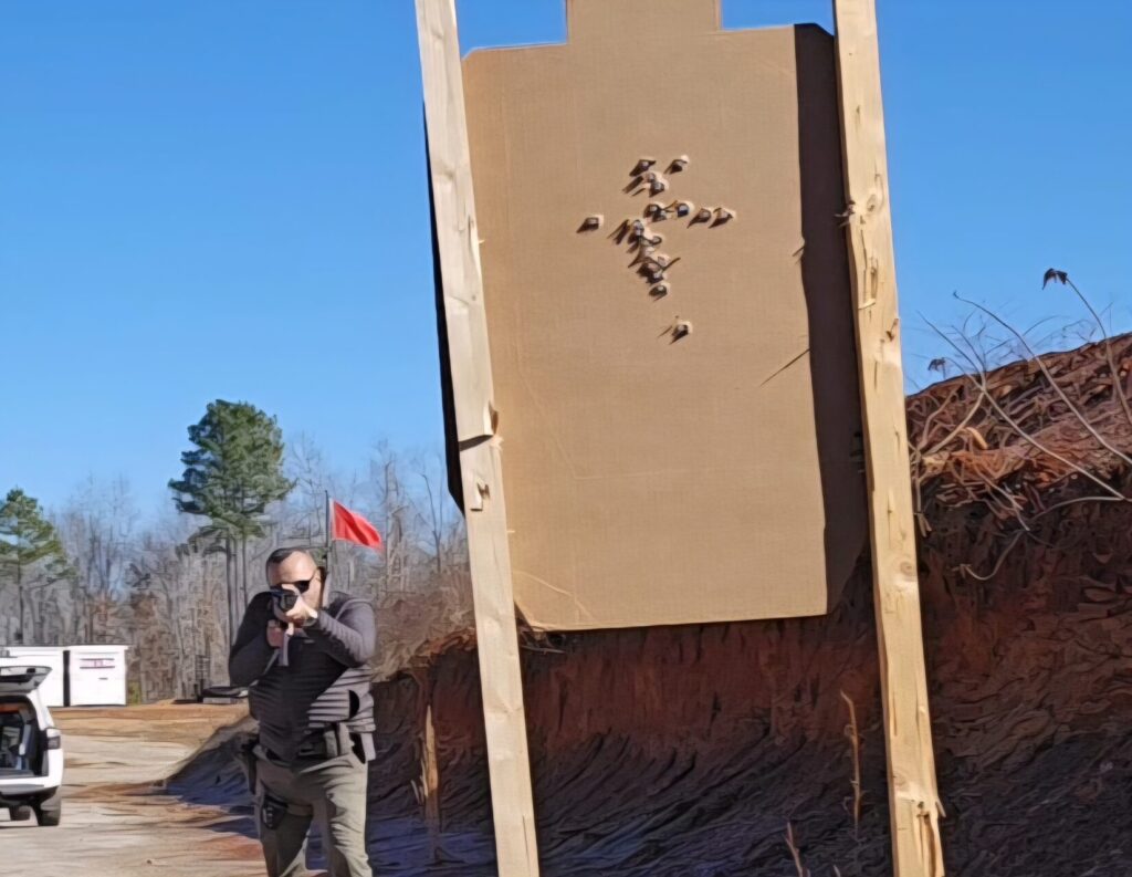 The back of a target and a shooter aiming a firearm downrange