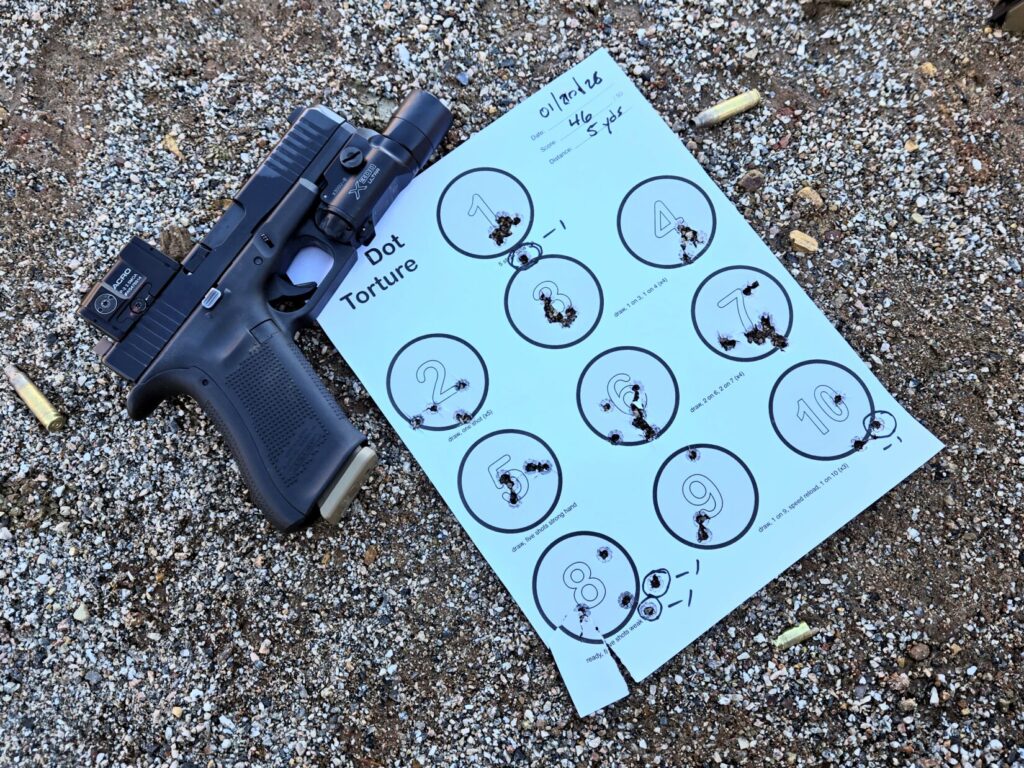 A pistol on the ground next to a dot torture target