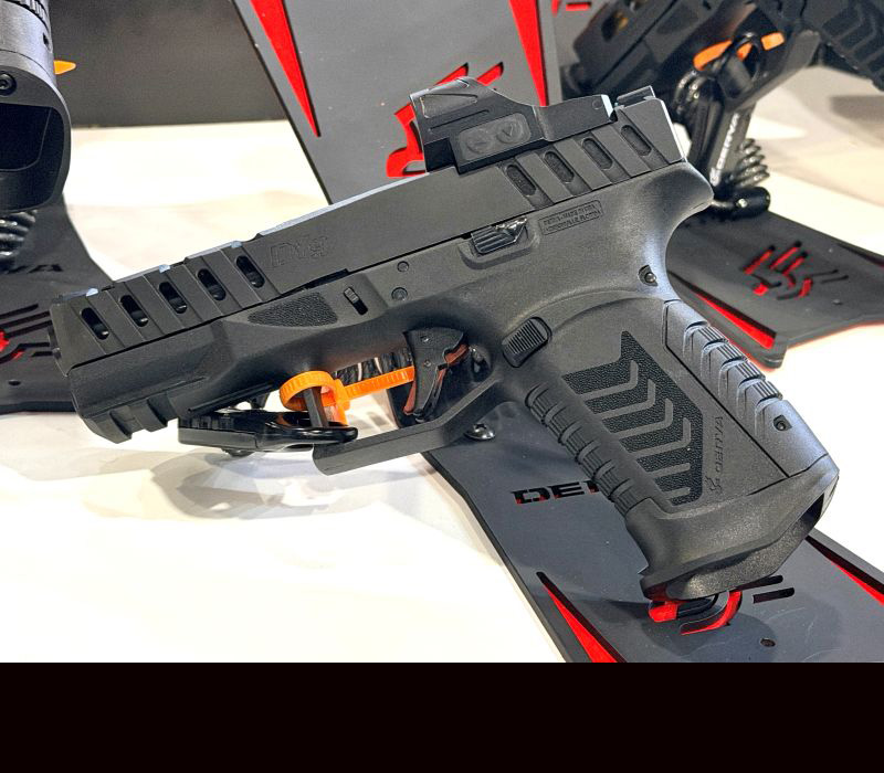 A black gun on a table during a trade show.