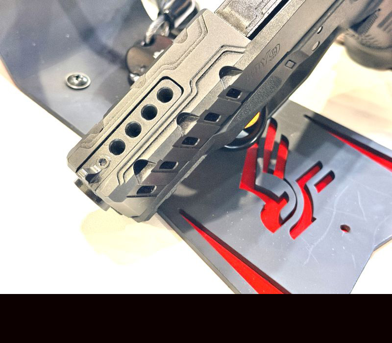 A look at the end of a barrel on a black gun, showing ports in the top of the barrel.