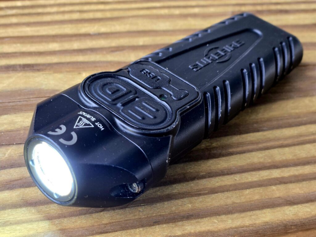 A flashlight with multiple buttons on a wood backdrop.