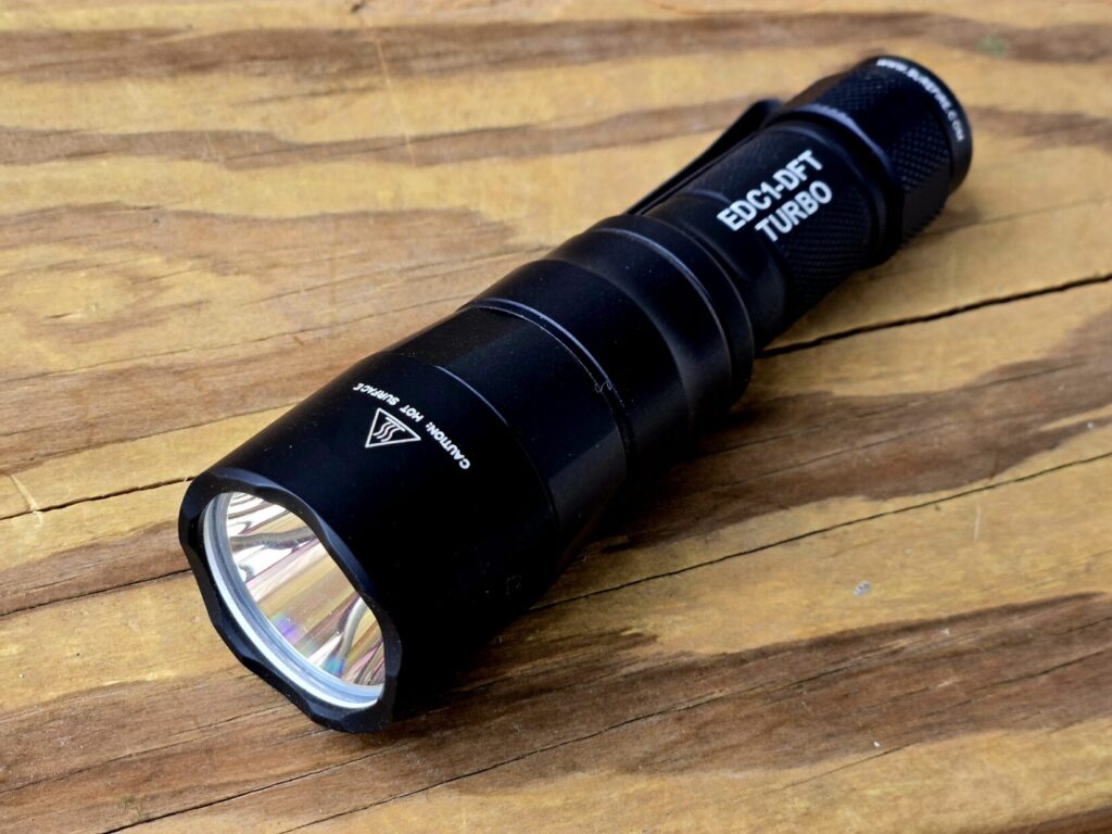 A Surefire flashlight against a wood backdrop