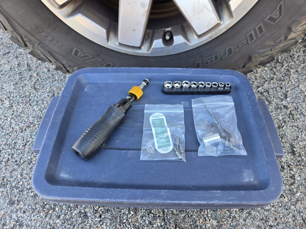 A torque wrench next to a tire on top of a Rubbermaid bin