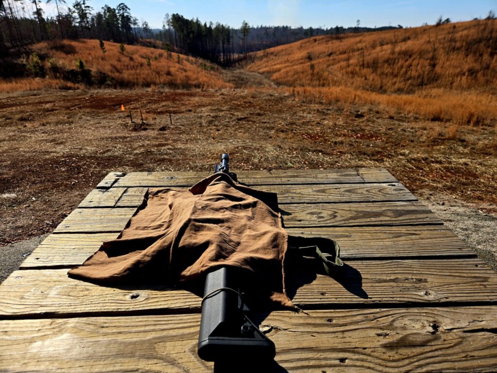 A rifle on a wooden bench at a shooting range.