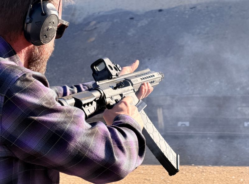 A man holding a shotgun out in front of him as he prepares to fire. 