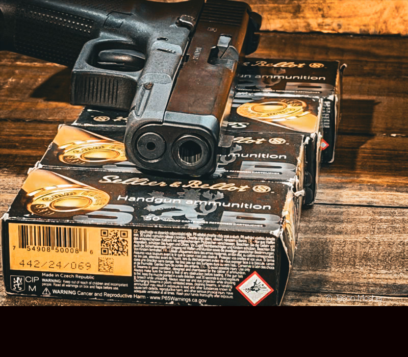 A black handgun laying on several boxes of ammo. 
