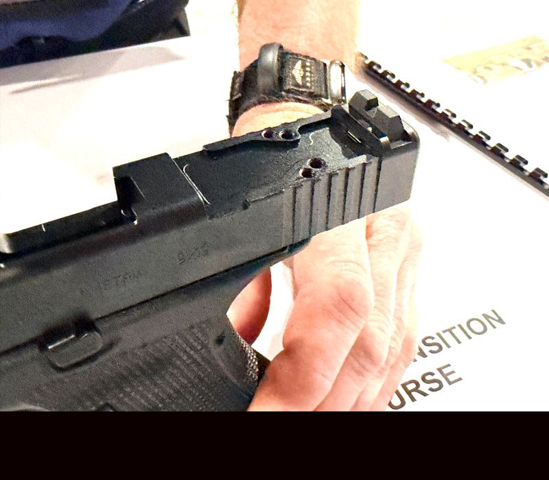 A black gun with the slide locked back, showing the area where the optic will mount. 