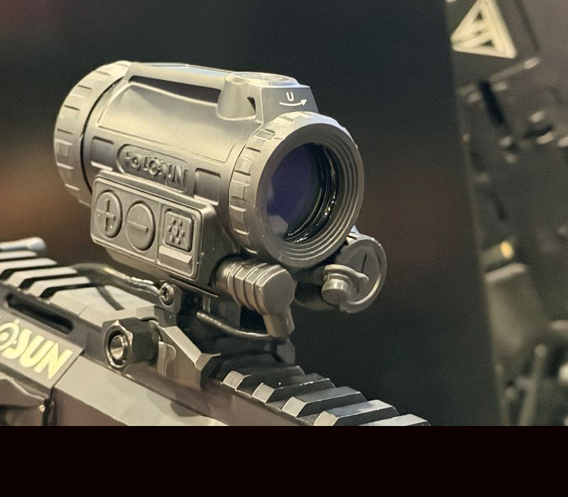 A black optic on a rifle showing the rounded portion on the back of the optic on display at a gun show.