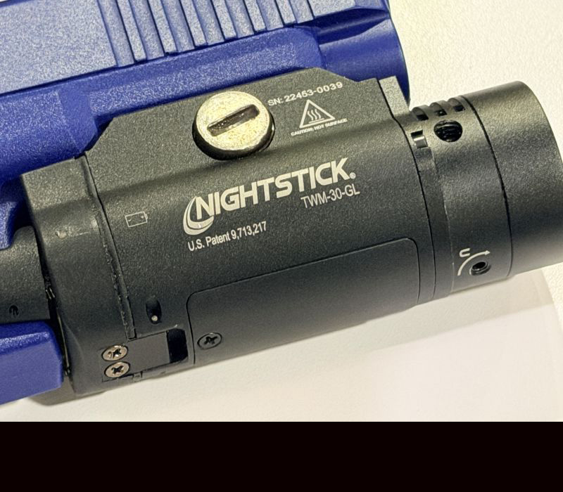 A black weaponlight light on a blue training, handgun.