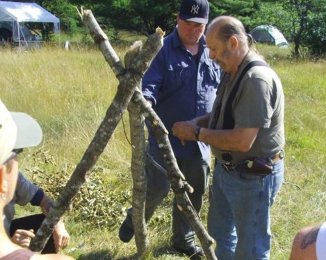 Two men construct a tripod during a wilderness survival course