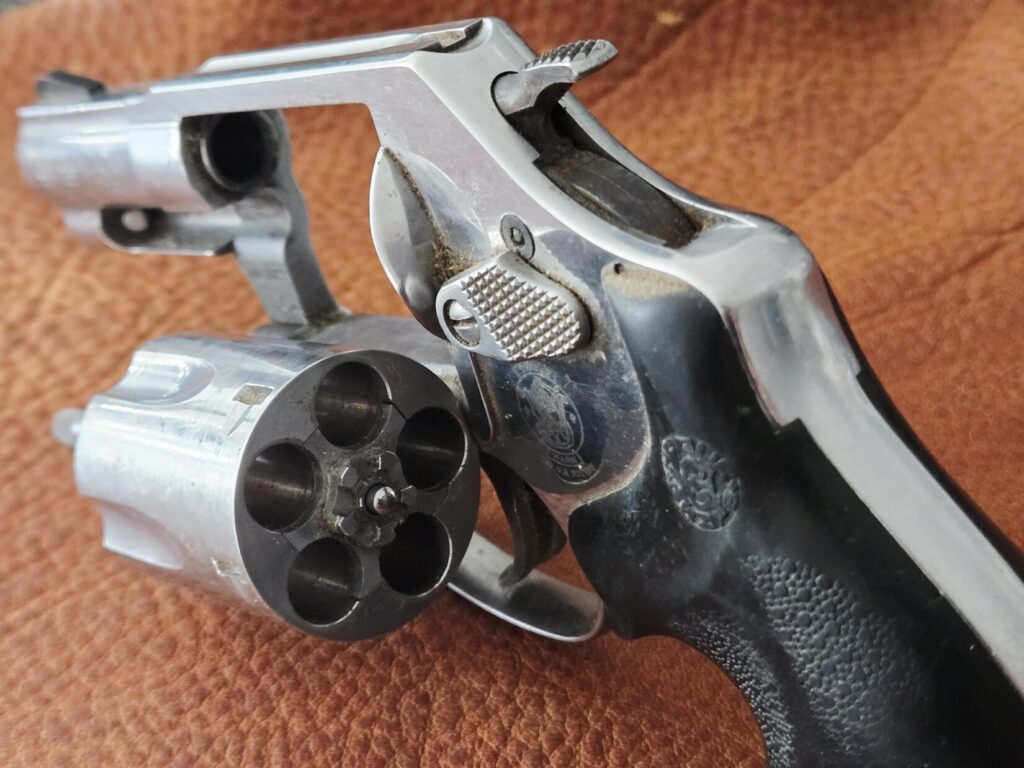 An unloaded revolver on top of a leather background