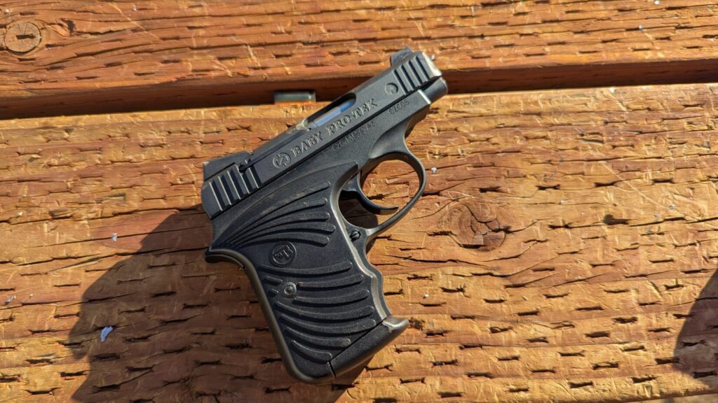 A close-up side view of a CZ Custom "Baby Pro-Tek" pistol resting on a wooden surface