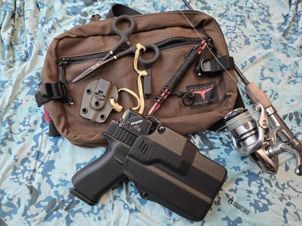 A fishing pack, hemostats, pistol, and fishing reel on a water camouflage background