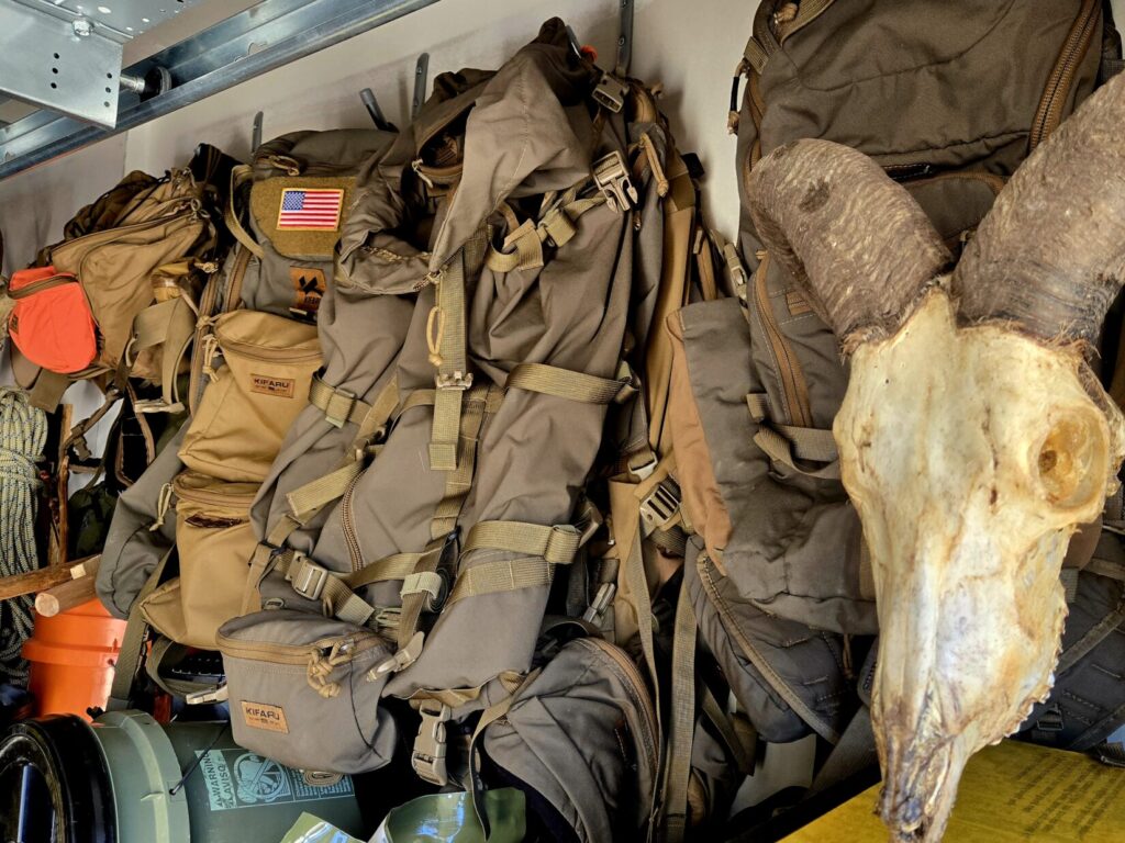 Backpacks hanging in a garage with a skull nearby