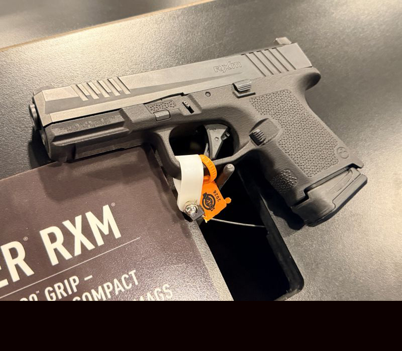 A black RXM handgun laying on a black tabled during a gun show.