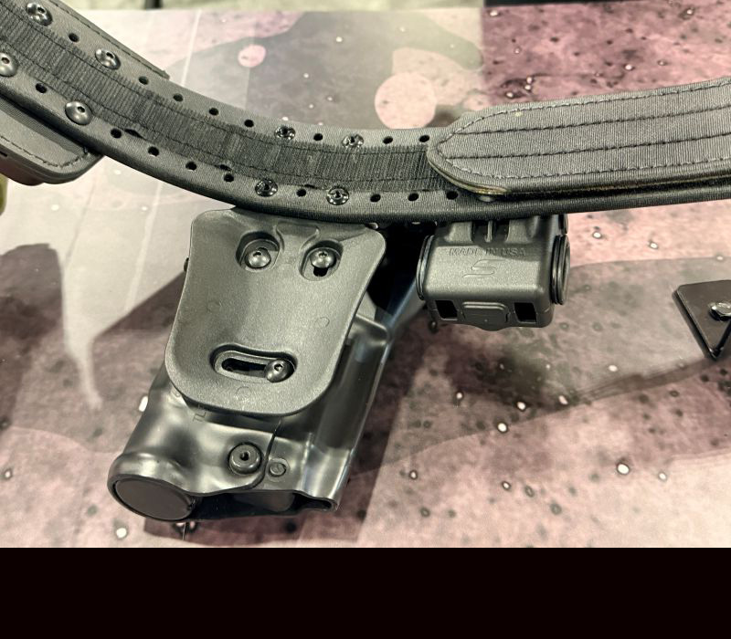 A view of the back of a holster that is attached to the MOLLE belt using four screws. 