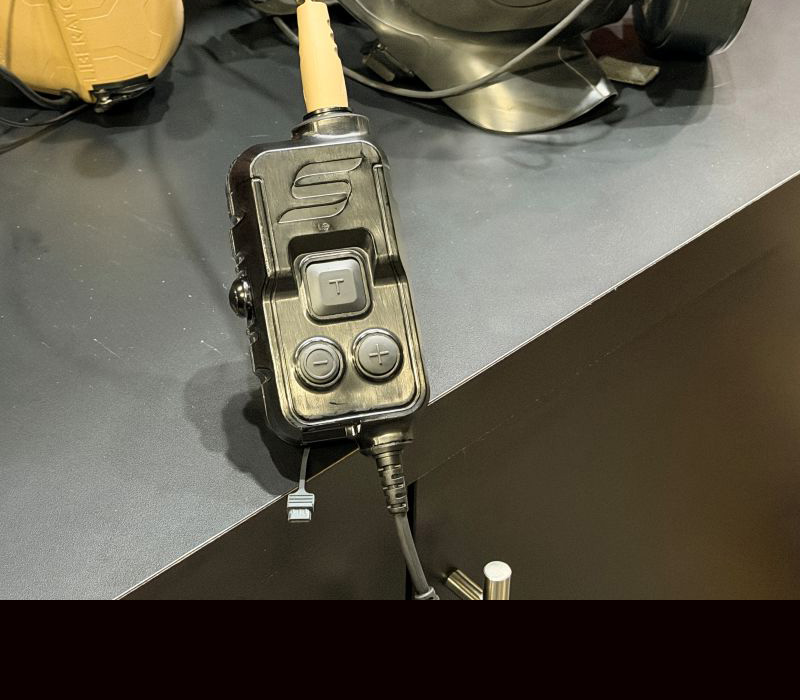 A black box with a button in the middle and cords attached on each end. 