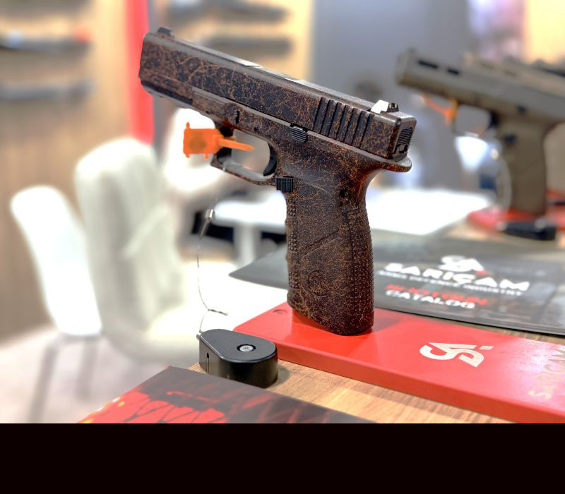 A black gun with red designs over it, mounted on a red gun stand.