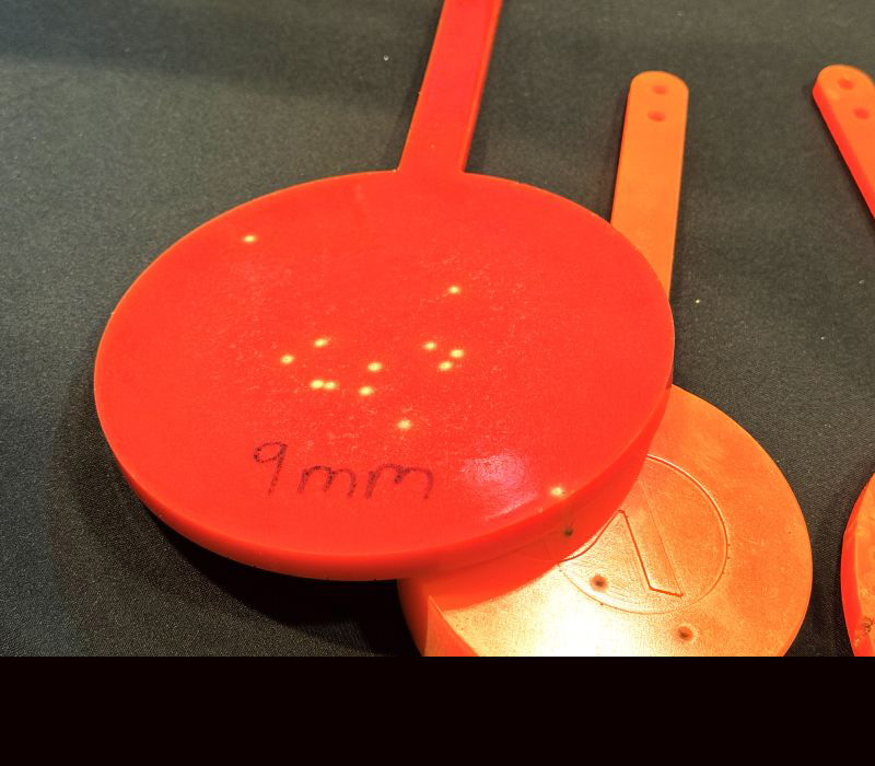 A red gong style target laying on top of an orange one on a black table. 