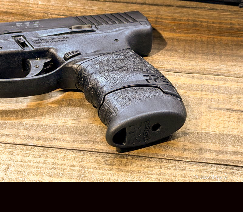 A black Walther PPS M2 laying on a wood table.