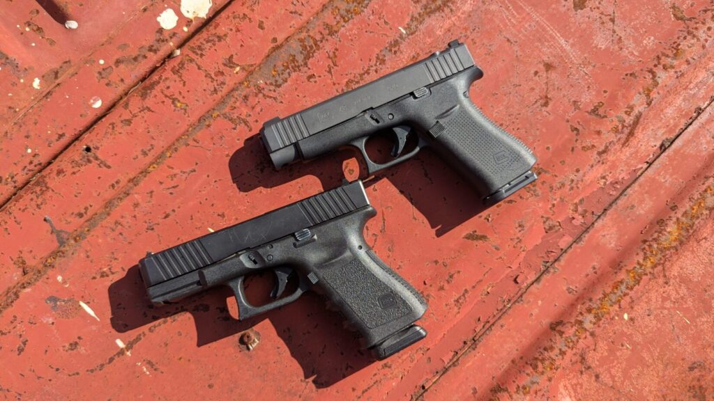 High-angle shot of two black Glock pistols lying on a weathered red metal surface.