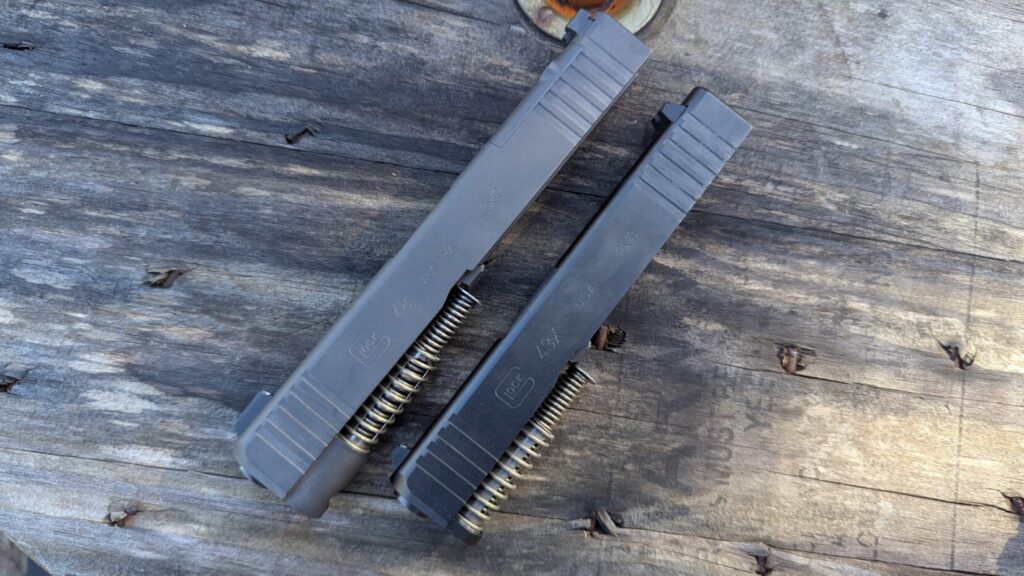 Close-up of two Glock slides (43X and 48) showing internal recoil springs and markings.