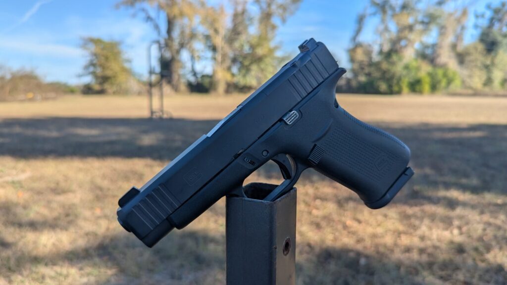 Profile view of a Glock 48 pistol balanced on a metal post outdoors.