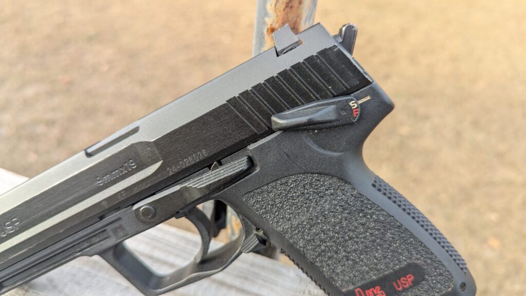 A close-up of the rear of the slide and frame, highlighting the hammer, safety selector (S/F), and slide release lever.