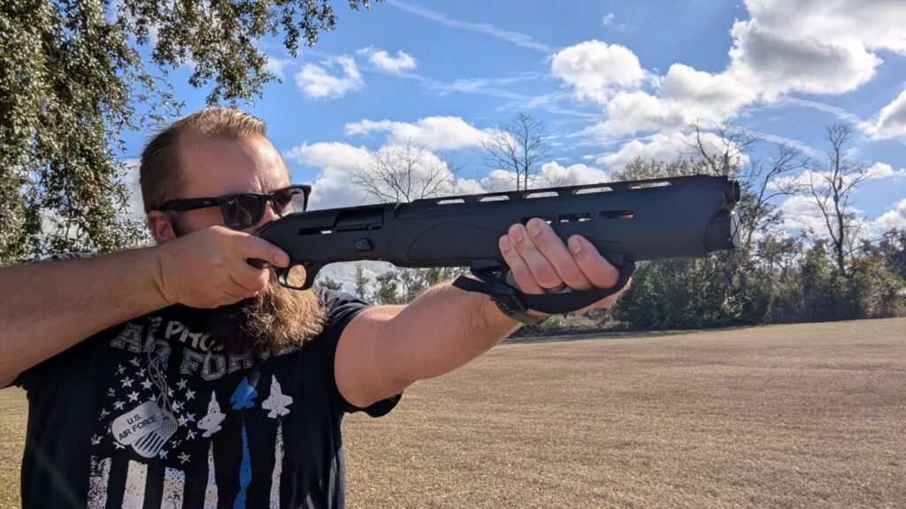 A man with a beard and sunglasses aiming the IWI Mafteah at a shooting range.