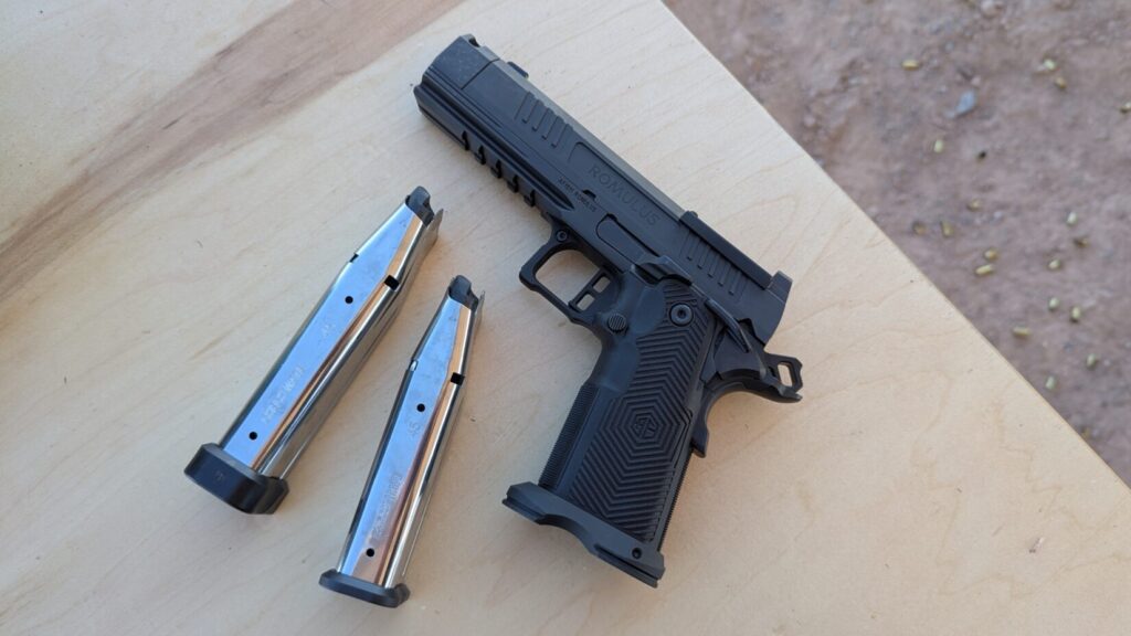 black Alpha Foxtrot handgun and two silver magazines displayed on a wooden surface.