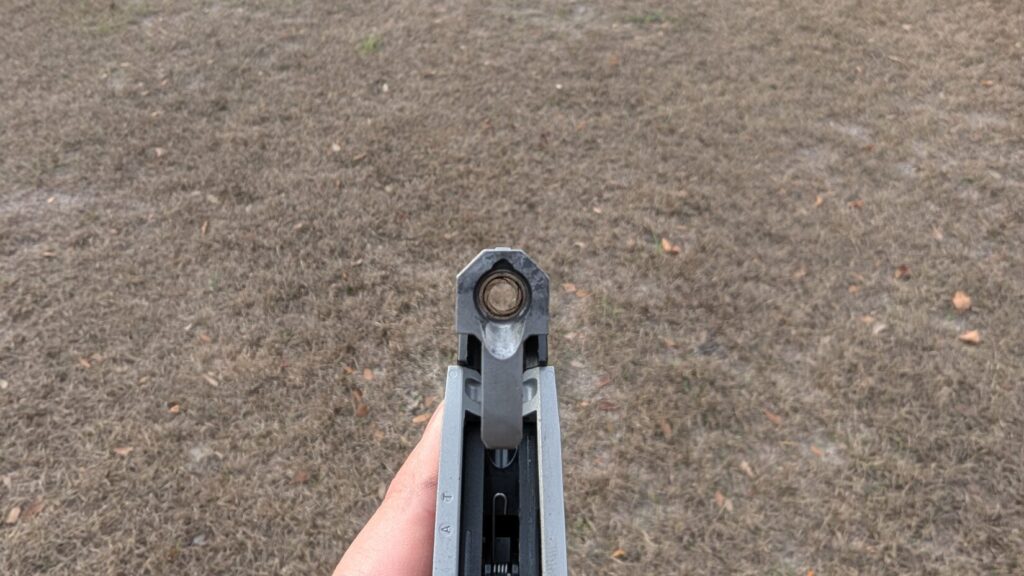 Top-down view of the Taurus 22TUC with the barrel tipped up, revealing the empty chamber.