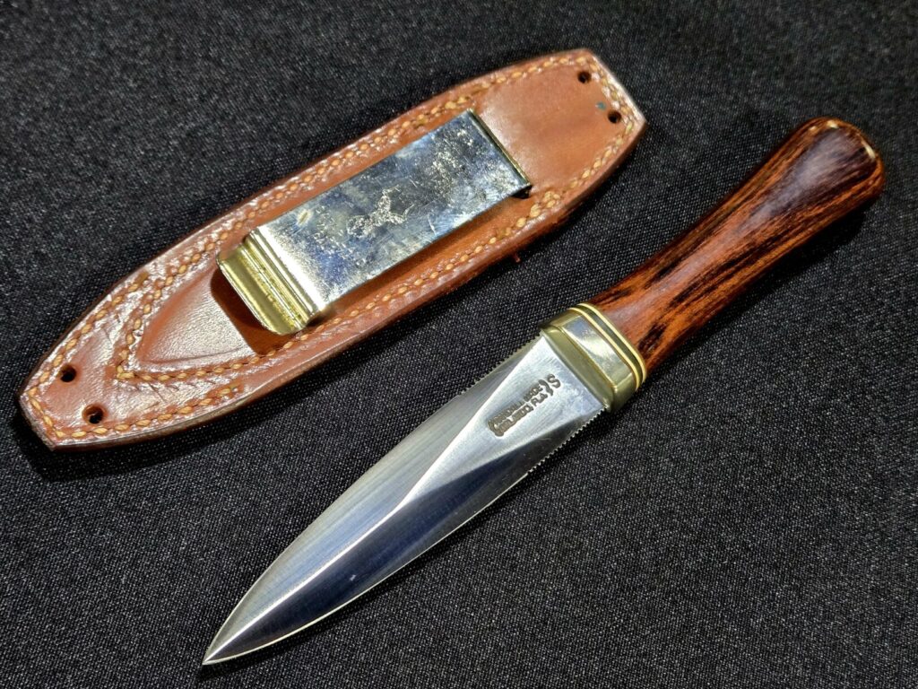 A knife and knife sheath against a black background at Dallas Safari Club