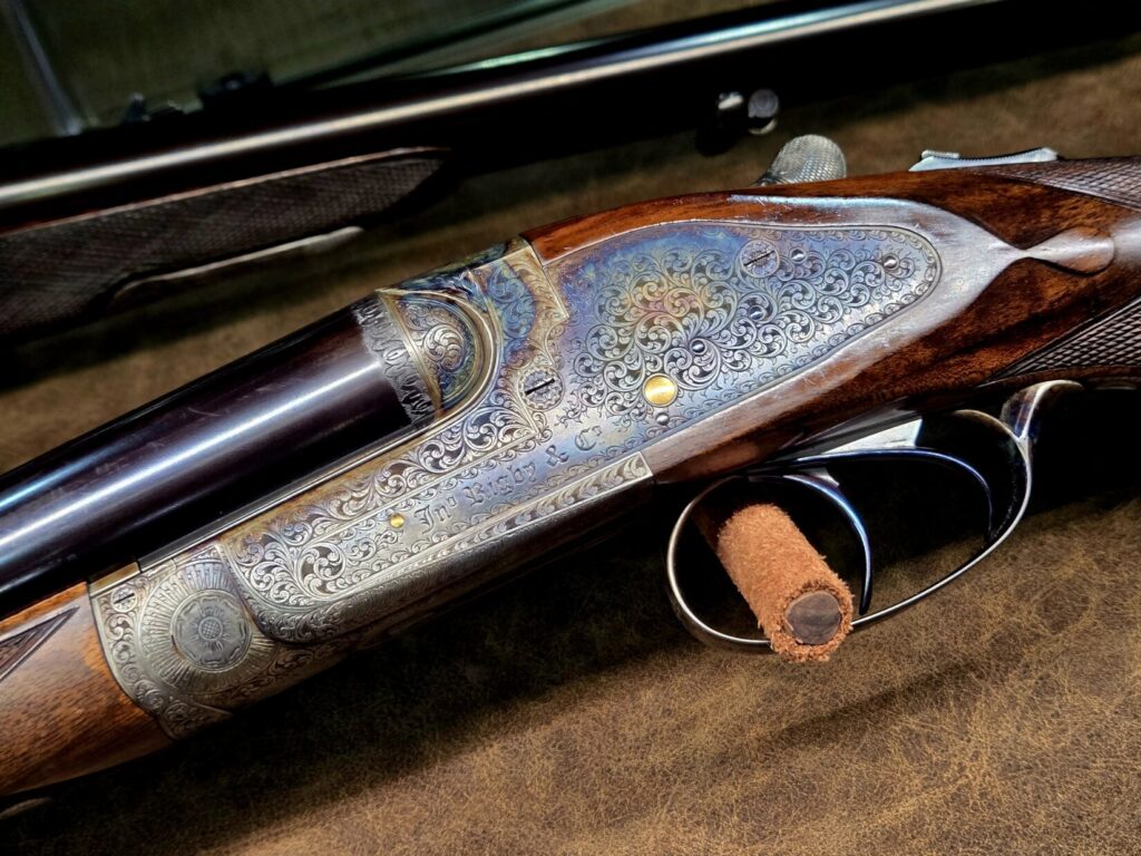 A highly engraved firearm receiver with wooden stock and deep blueing.