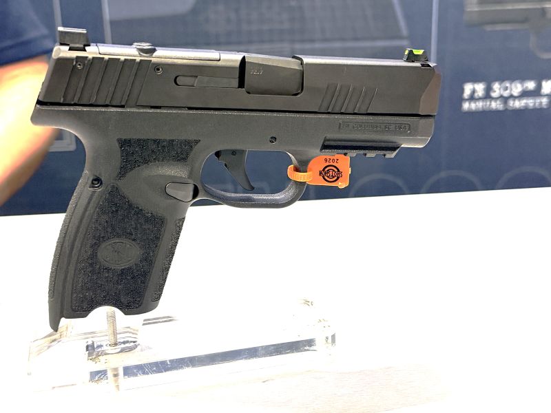 A black gun on a stand at a gun show with a blue background behind it. 