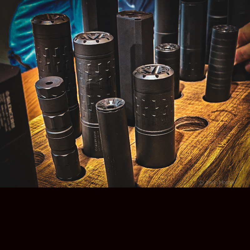 A wood holder with multiple silencers standing upright inside of it. 