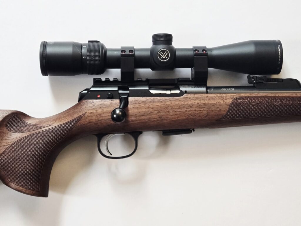 A bolt action rifle and optic against a white background