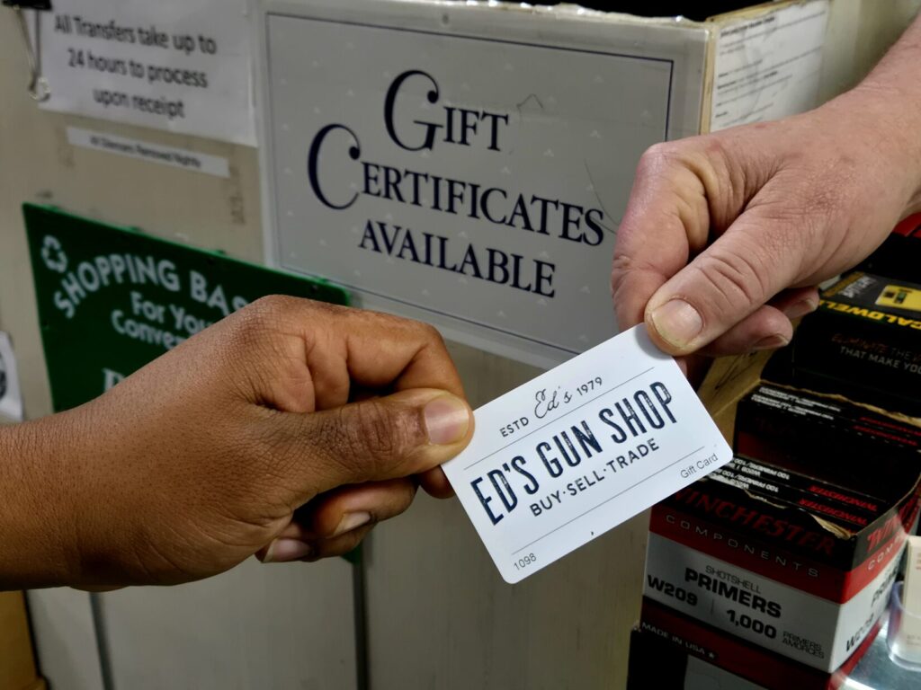 a gift card is passed from one person to another at a gun counter