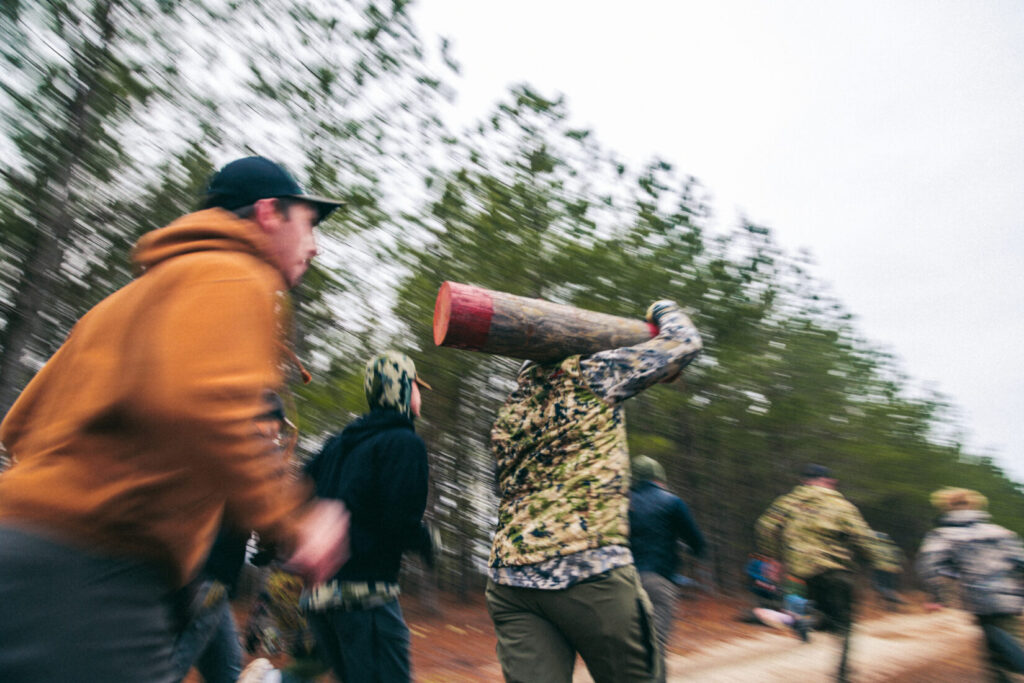 A group of athletes running with a wooden log