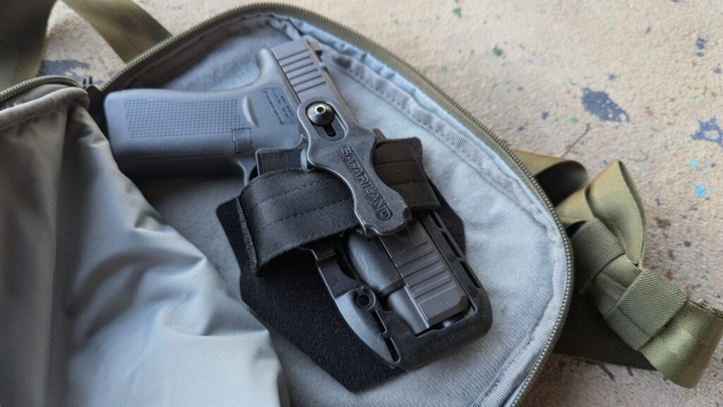An open olive green waist bag reveals a Glock pistol secured inside a black Safariland holster system.