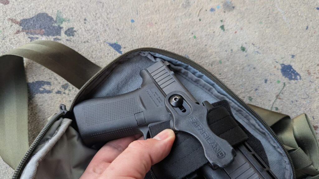 A hand reaching into an open tactical bag to demonstrate the fit of a holstered Glock pistol.